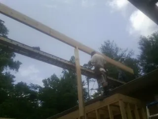 Carpenter setting a ridge beam over a new addition frame — Ice Dam Removal by Roofing Brothers in Rivesville