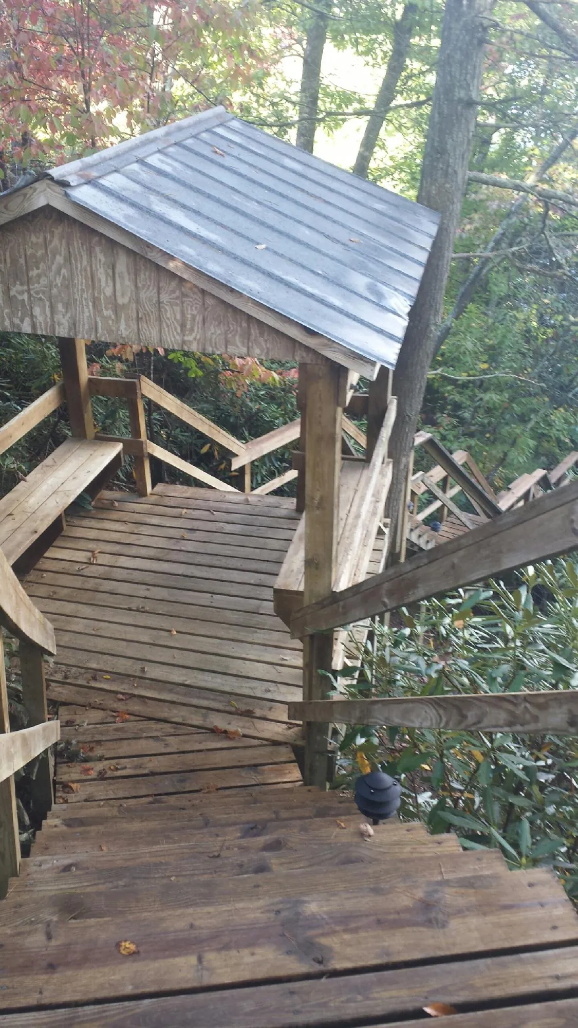 Metal roofed shelter over wooden steps on a wooded walkway — Skylight Repair & Installation work by our crew in Rivesville