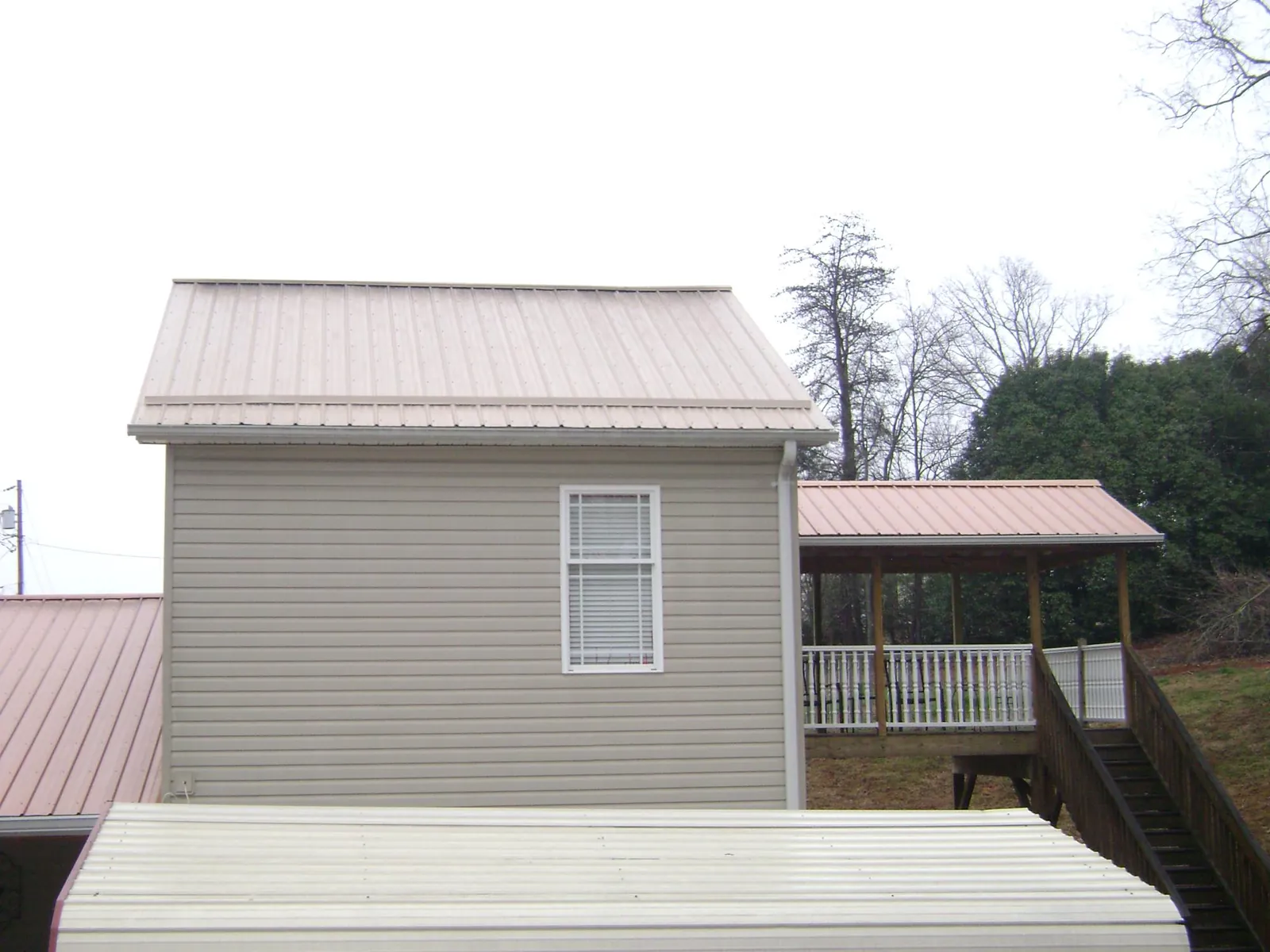 Tan metal roofs on a two story addition and attached porch, from a Roof Replacement job in Rivesville