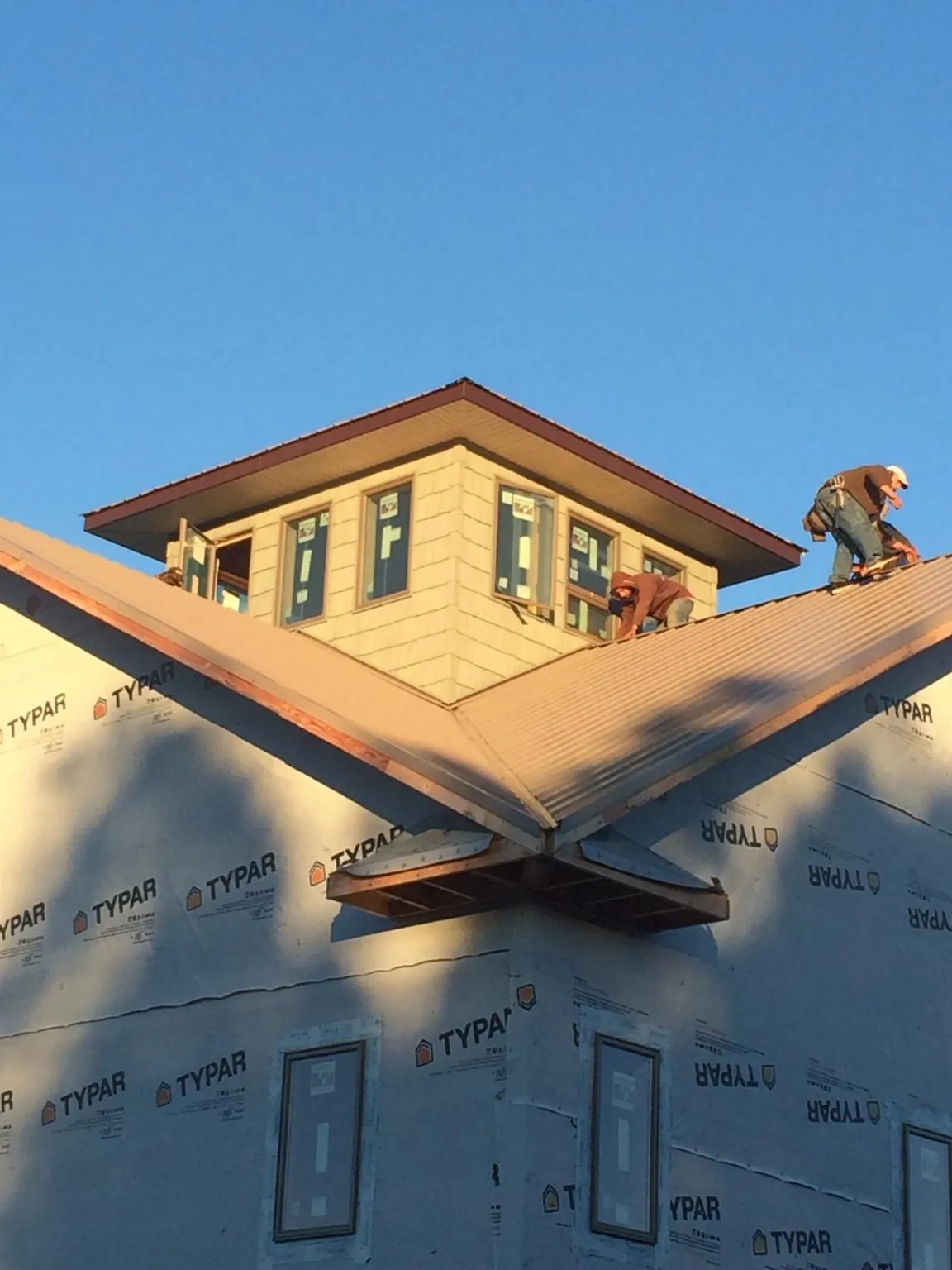 Roofers working around a rooftop cupola on a new metal roof at sunset — Roof Waterproofing in Rivesville by Roofing Brothers
